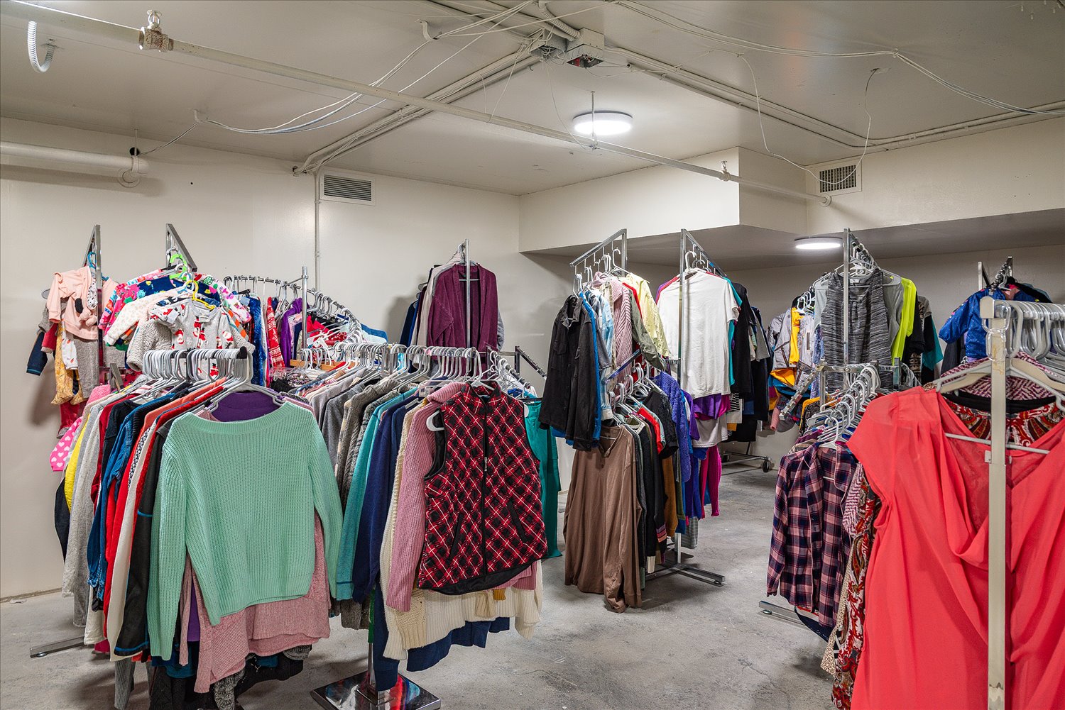 A storage room of hanging donated clothing, sorted and ready for distribution.