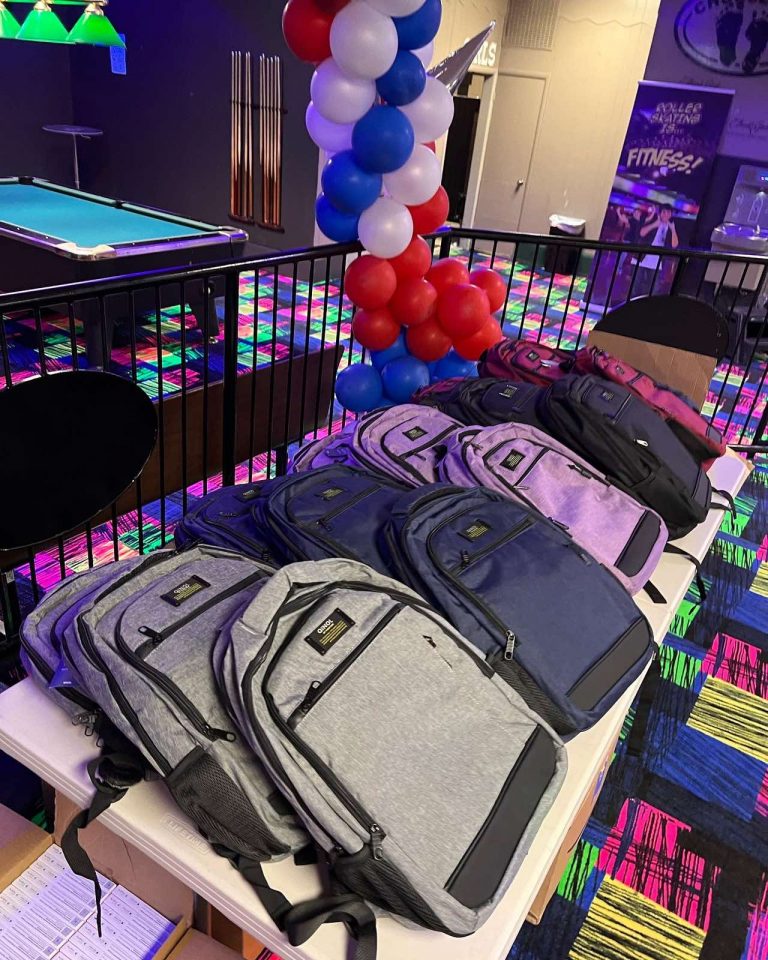 Backpacks laid out for a community giveaway beneath a red, white, and blue balloon arch at an SSA event.