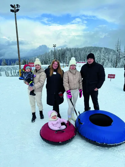 A family enjoying winter snow tubing together on a Cultural Integration Program outing.