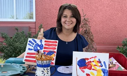 smiling-woman-with-drawings-of-palm-prints-in-the-colors-of-the-us-and-ukrainian-flags.webp